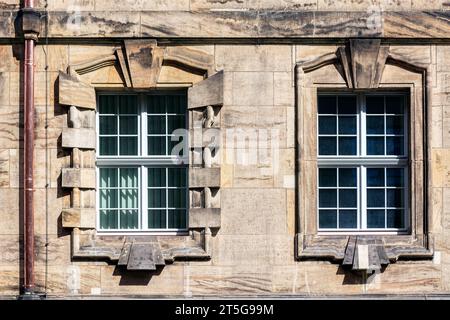 Two rectangular windows on the wall made of stone blocks and a copper downpipe. From the Windows of the world series. Stock Photo