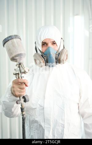 Serious worker with painting tool in hand standing in workshop Stock Photo
