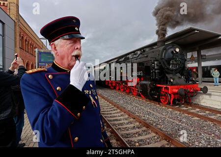 Blankenburg, Germany. 05th Nov, 2023. Railroad fan Winfried Rettig stands in the historic uniform of a royal Prussian railroad master during a special trip with an old steam locomotive at Halberstadt station. The special trip with steam locomotive 95 027 was organized to celebrate the 100th birthday of the steam locomotive. The Rübelandbahn working group had the historic steam locomotive run from Blankenburg to Halberstadt on two days. Credit: Matthias Bein/dpa/Alamy Live News Stock Photo