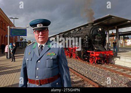 Blankenburg, Germany. 05th Nov, 2023. Railroad fan Winfried Rettig stands in the historic uniform of a royal Prussian railroad master during a special trip with an old steam locomotive at Halberstadt station. The special trip with steam locomotive 95 027 was organized to celebrate the 100th birthday of the steam locomotive. The Rübelandbahn working group had the historic steam locomotive run from Blankenburg to Halberstadt on two days. Credit: Matthias Bein/dpa/Alamy Live News Stock Photo