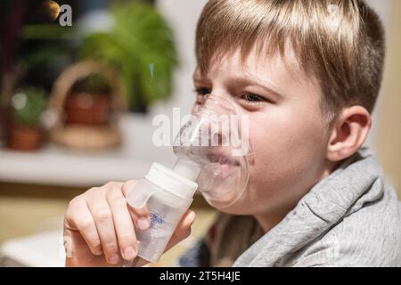 A child uses alternative medicine to treat asthma and breathes medication through a nebulizer at home. Real People Stock Photo