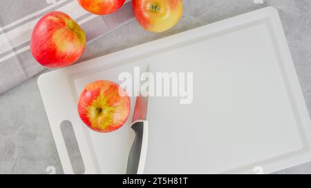 Red apples and a knife close-up on a white cutting board, flat lay with copy space Stock Photo