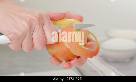 Woman hands peeling red apple. Close-up view, apple cake recipe Stock Photo