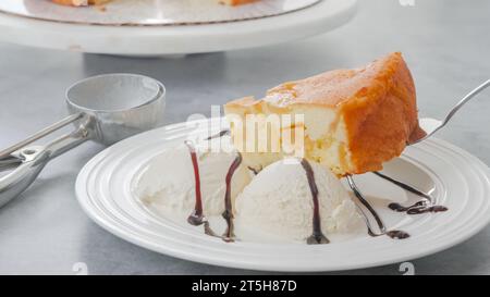 Slice of a freshly baked apple cake with whipped cream topping, served with vanilla ice cream and chocolate close-up on a white plate Stock Photo