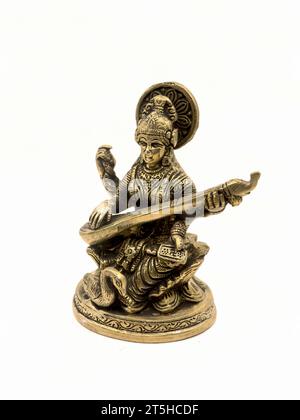 brass statue of saraswathi, goddess of knowledge, art, music, nature and wisdom sitting on a lotus near a swan playing veena instrument Stock Photo