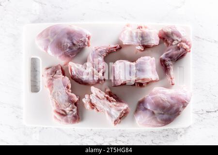 Pieces of portioned rabbit on a white cutting board - Top of view. ​ Stock Photo
