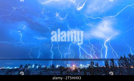 A huge amount of lightning in the night sky on the river bank. Stock Photo