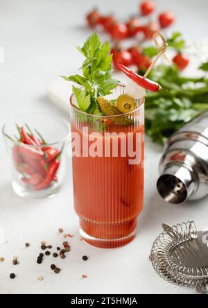 Cocktail bloody mary vodka and juice mix with peppers and celery on light board. Stock Photo