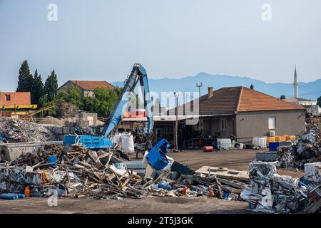 Grab crane works in waste recycling and sorting center. Scrap metal recycling center for sorting metal, aluminum, brass, copper, stainless steel from Stock Photo