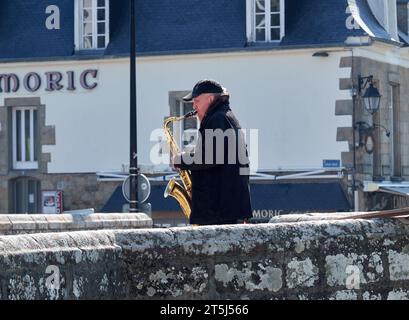 Man playing a saxophone on a bridge Stock Photo