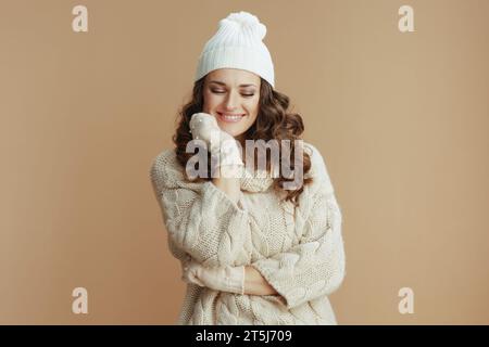 Hello winter. happy stylish woman in beige sweater, mittens and hat isolated on beige background. Stock Photo