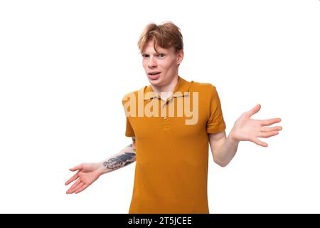 a young guy with short red hair dressed in a summer T-shirt feels confused Stock Photo
