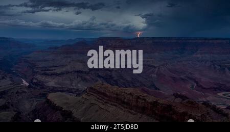 Distant and dreamy lightning strikes beyond the north rim seen from the Grand Canyon during twilight’s blue hour. Stock Photo