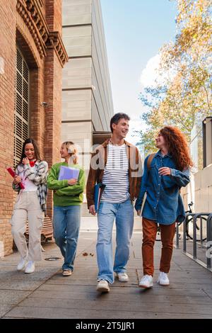 Vertical. Group of smiling high school teenage students walking before starting class, talking together. Diverse classmates carrying notebooks and backpacks going along university. Academy people. High quality photo Stock Photo