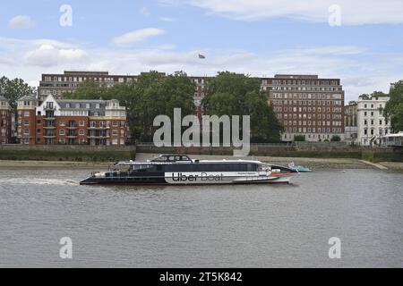 A view of Dolphin Square in Pimlico on the banks of the River Thames in London with a passing Uber Boat in the foreground Stock Photo