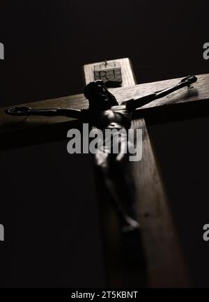 Jesus on the cross looking down on his followers. The crucifixion. A darked sihouetted figure on a timber cross with a black background Stock Photo