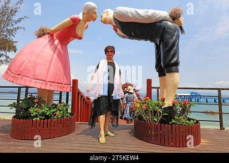 Sanya City, Hainan - March 31, 2019: A lady before a cartoon lover sculpture on Wuzhizhou Island，Sanya City, Hainan Province, China Stock Photo