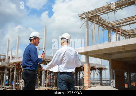 Two engineer working and checking plan on construction site. Stock Photo