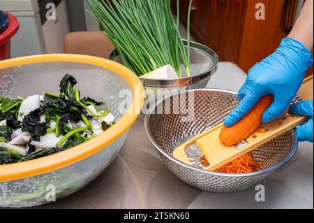 The process of making a traditional Korean dish, kimchi. A woman wearing gloves is preparing various ingredients needed for the kimchi. Stock Photo