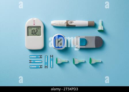 Top view of glucometer, lancet pen and strips on blue background. diabetes test kit Stock Photo