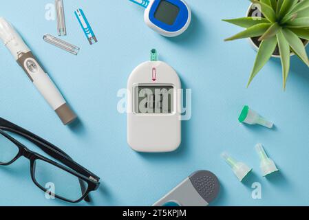 Top view of glucometer, lancet pen and strips on blue background. diabetes test kit Stock Photo