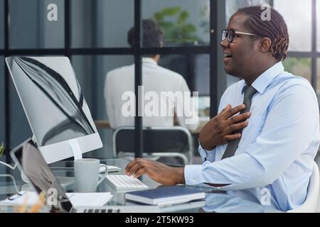 a man at a workplace at a table in front of a computer is surprised by the good news Stock Photo