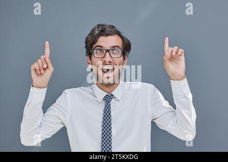 young successful man on a gray background showing fingers up Stock Photo