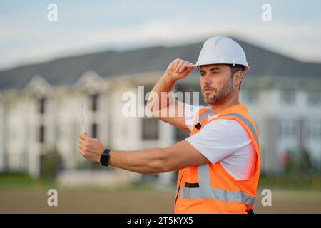 Portrait of builder man. Construction worker with hardhat helmet on construction site. Construction engineer worker in builder uniform. Worker Stock Photo