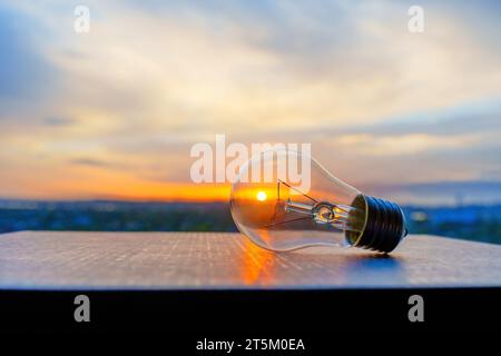 Close-up view a light bulb with dramatic sky and setting sun glowing through. Solar energy related concept. Stock Photo