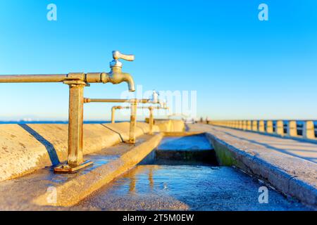 Low-angle view of the public washing station at the Cabrillo Pier set against a bright blue sky on a sunny winter day. Stock Photo