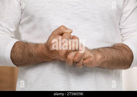 Man cracking his knuckles on blurred background, closeup. Bad habit Stock Photo