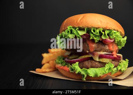 Tasty burger with vegetables, patties and lettuce served on wooden table, closeup. Space for text Stock Photo