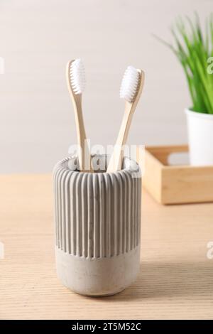 Bamboo toothbrushes in holder on wooden table Stock Photo