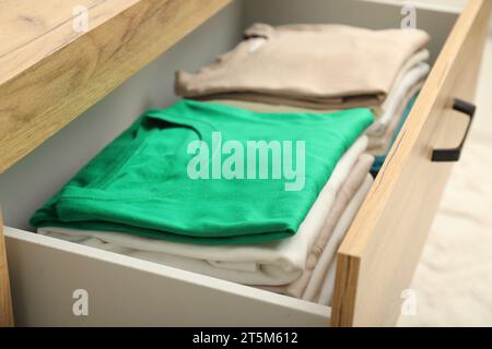 Stacks of different folded shirts in drawer indoors, closeup. Organizing clothes Stock Photo