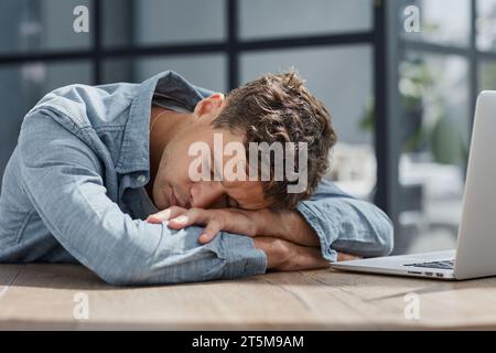 young office man at a laptop sleeping at his workplace Stock Photo