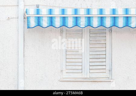 Closed white window shutters with blue awnings, detail from croatian seaside, copy space included Stock Photo