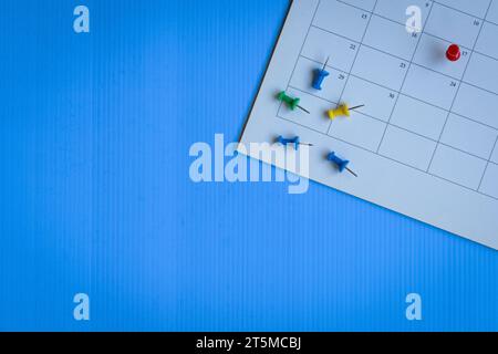 Calendar with red and colorful pins, top view. Copy space. Stock Photo
