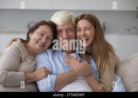 Cheerful adult woman hugging older senior parents Stock Photo