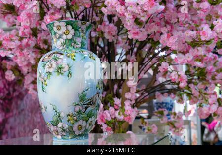 Ceramic vase in an antique style with floral patterns on a background of spring flowers. Stock Photo