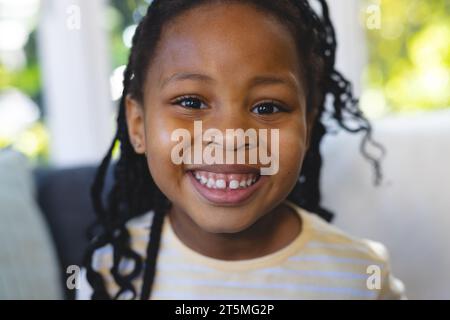 Portrait of happy african american girl in bright living room at home, copy space Stock Photo