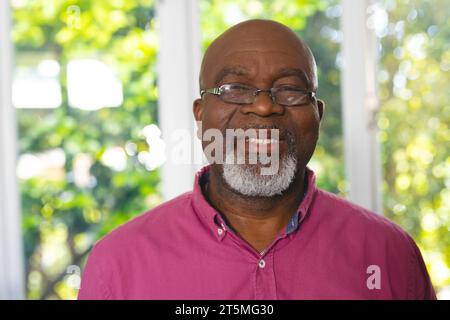 Portrait of happy senior african american man wearing glasses in living room at home, copy space Stock Photo