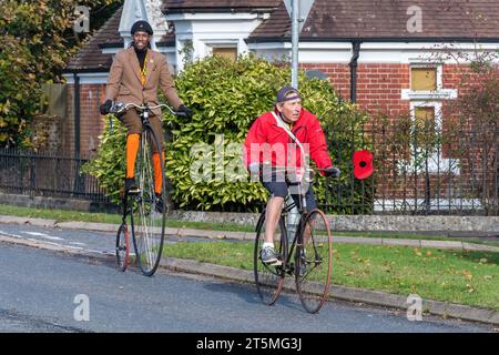 5th November 2023. Participants in the London to Brighton Veteran Car Run 2023 driving through West Sussex, England, UK. The route of the popular annual event runs for 60 miles. Two men riding old bicycles, one of them on a penny farthing. Stock Photo