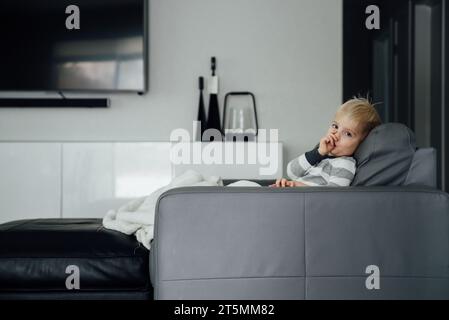 Side view of little boy looking at camera and sucking thumb. Stock Photo