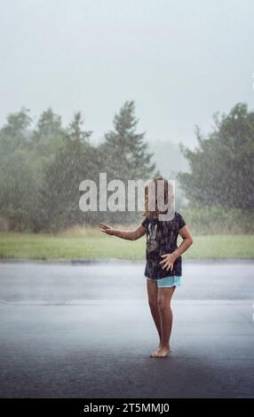 Young girl playing in the rain in summer Stock Photo