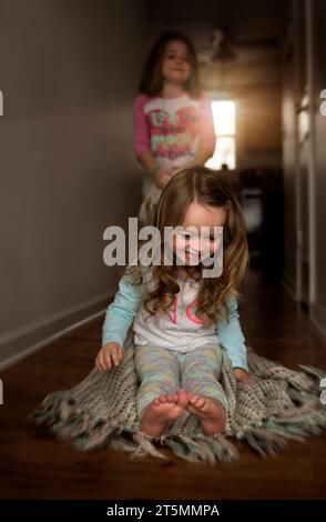 Young sisters playing and laughing in hallway of home Stock Photo