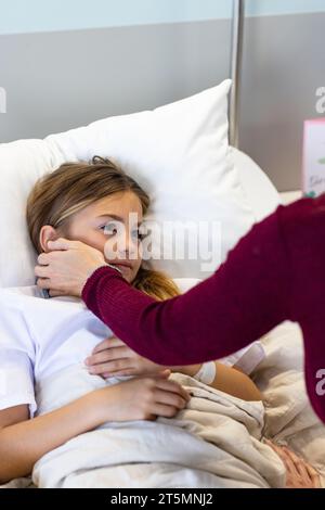 Caucasian mother comforting sick daughter patient lying in hospital bed, copy space Stock Photo
