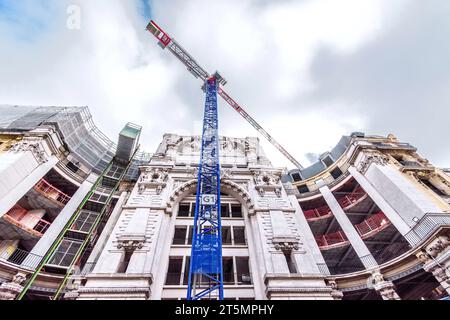 Tall Liebherr construction crane in front of the Les Anciens Magasins Dufayel building on the Rue de Clignancourt, Paris 18, France. Stock Photo