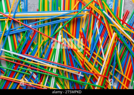 many multi-colored plastic tubes for cocktail on Colored background, top view. Stock Photo