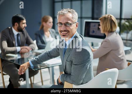 Diverse group of smiling businesspeople talking together around Stock Photo