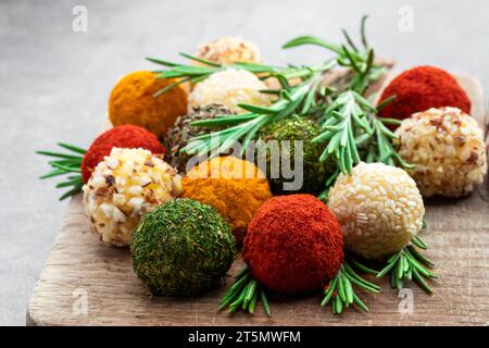 Cheese  balls covered with various spices and nuts decorated with rosemary sticks on gray background Stock Photo